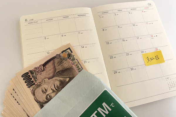 支払日が記された手帳と現金