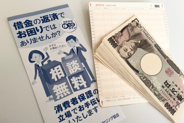 借金返済相談のパンフレットと通帳と現金